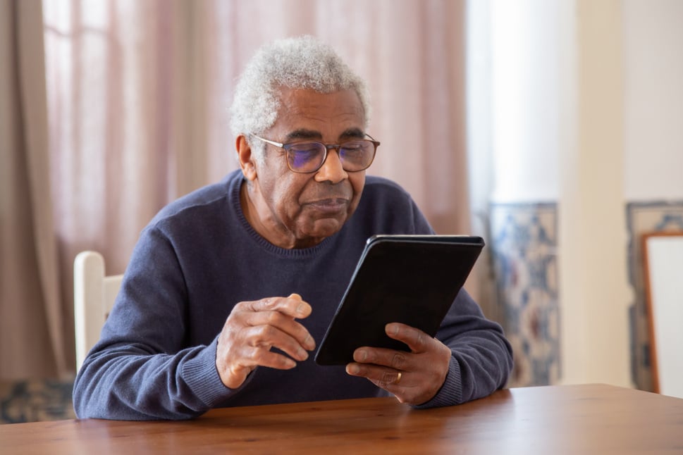 An Elderly Man in Black Sweater Using a Digital Tablet